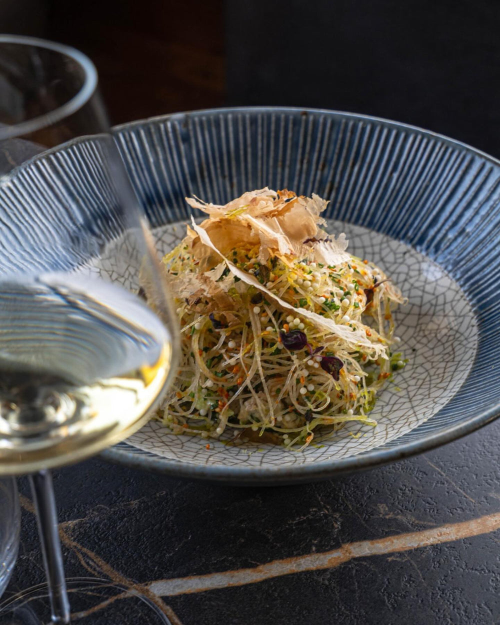 Assiette de cuisine japonaise aux pousses et copeaux de bonite, verre de vin blanc, restaurant Nice